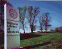 National Library of Medicine complex, looking west from Rockville Pike, Summer (photograph, 8-bit color, GIF87 format, 98 pixels high, 124 pixels wide, 9005 bytes)